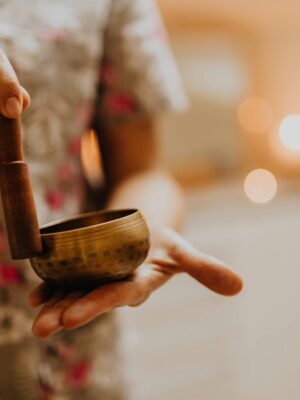 Close-up of a person using a singing bowl for meditation, promoting relaxation and wellness.